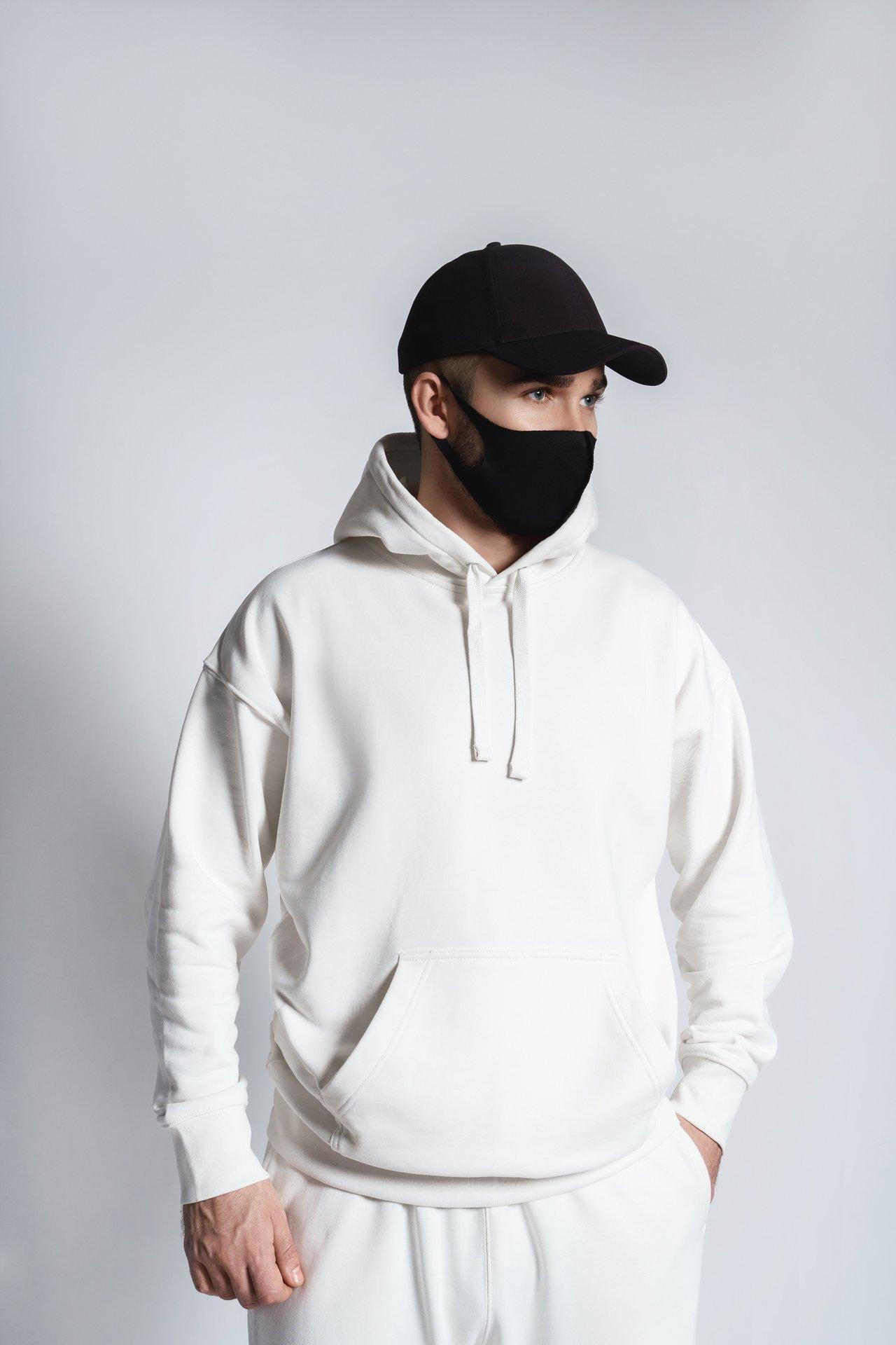 Jeune créateur de streetwear portant un hoodie blanc dans un studio de collaboration urbaine.