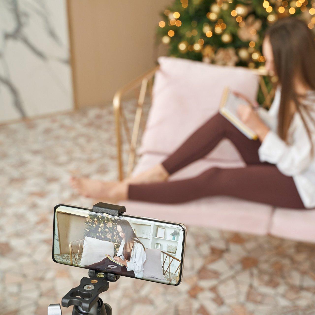 Jeune créatrice de contenu filmant un Reel Instagram dans un décor hivernal festif et chaleureux.