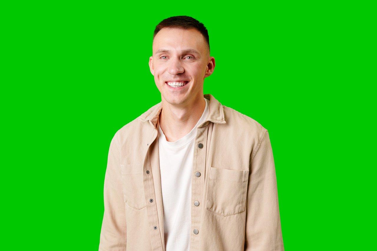 Miniature YouTube face : jeune homme souriant sur fond vert pour attirer l'attention en 2026.