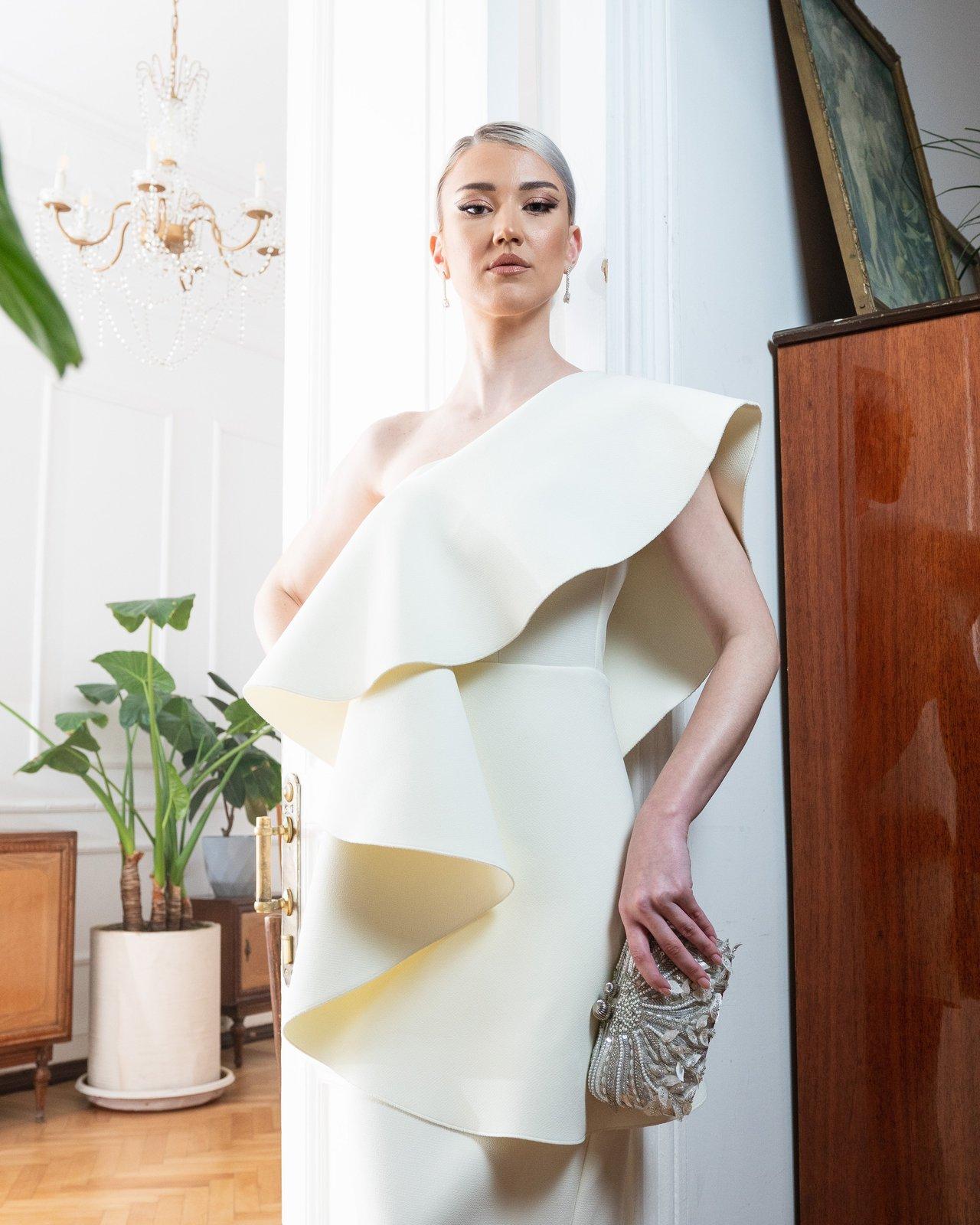 Portrait d'une femme élégante en robe blanche lors d'une collaboration de luxe entre créateurs et maison de mode.
