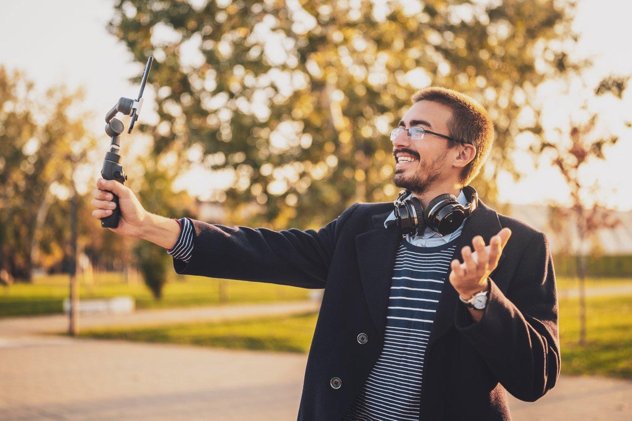 Un micro influenceur filmant un contenu vidéo original en extérieur avec un stabilisateur pour un blog professionnel.